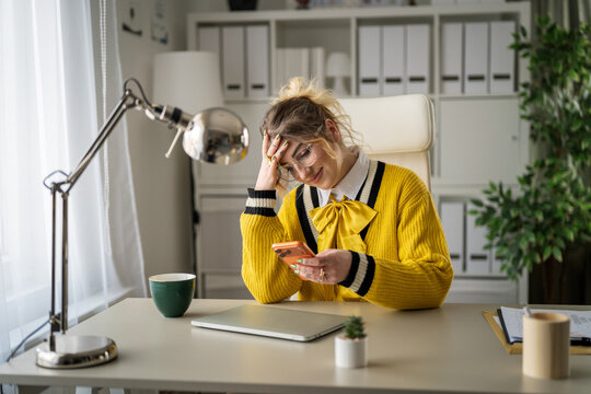 Woman procrastinating at work, smiling and using cell phone