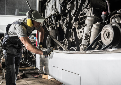 Worker Repairs Coach Bus Engine in Garage During Daytime Hours