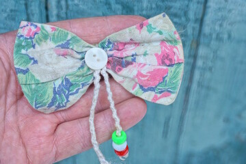  hand holds of clothing made of one color fabric bow tie with a white button in green background