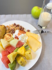 Breakfast in a restaurant with fresh sliced ​​fruits and vegetables with pancakes and diet food on a white plate on the table