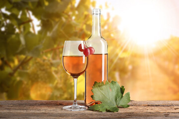 Naklejka premium Wine in glass and bottle on table in sunny vineyard