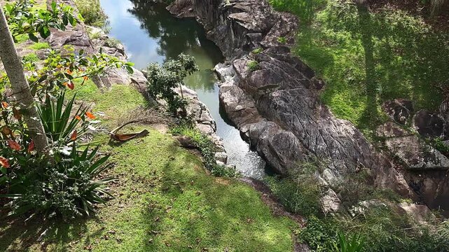 A river winds gently through a natural channel carved between rugged stone formations. 