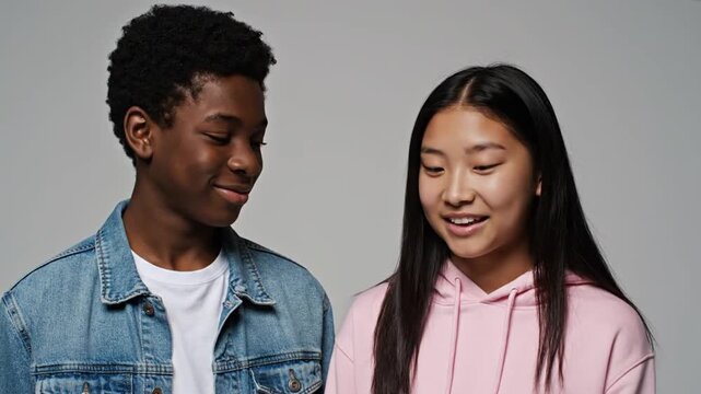 Two shy multiethnic teenagers smiling studio portrait