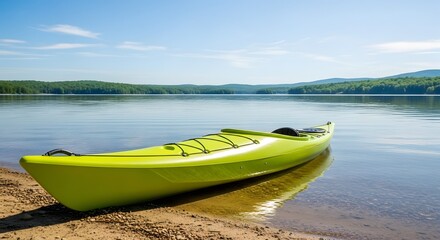 Vibrant green kayak on the sandy shore of a calm lake with forested hills under a blue sky.
