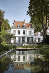 Fototapeta premium Beautiful old house stands beside a pond surrounded by green trees in the afternoon light in a calm neighborhood in France