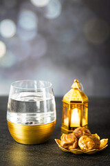 A glass of water, dates and a lantern on the table.