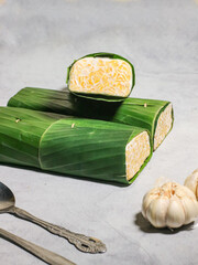 Tempeh wrapped in banana leaves with a marble background. Tempeh is a traditional Indonesian food made from soybeans. It is beneficial for health.