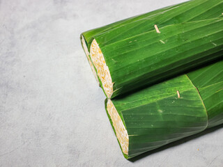 Tempeh wrapped in banana leaves with a marble background. Tempeh is a traditional Indonesian food made from soybeans. It is beneficial for health.