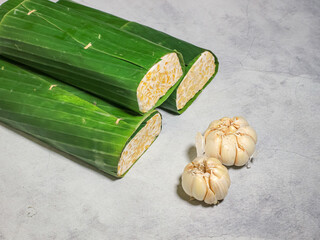 Tempeh wrapped in banana leaves with a marble background. Tempeh is a traditional Indonesian food made from soybeans. It is beneficial for health.