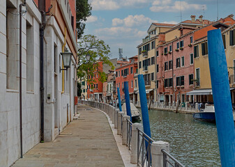 Venice water canal with ancient buildings facades and boats docked outside