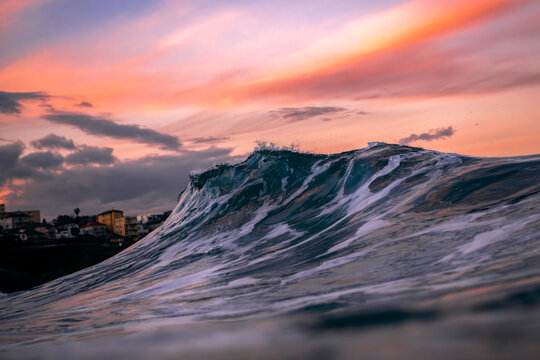 A breaking ocean wave at sunset at Bronte Beach, Sydney, Australia, with soft pink clouds and fading light reflecting across the water.
