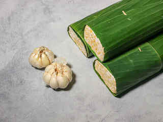 Tempeh wrapped in banana leaves with a marble background. Tempeh is a traditional Indonesian food made from soybeans. It is beneficial for health.