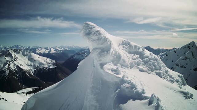 Snow patterns form on mountain tops in the daytime with clear skies and distant peaks visible from above