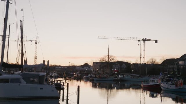 Sunset inside Eckernf&ouml;rde Harbor. Warm evening light reflects on calm harbor water with boats and piers, creating a quiet and atmospheric scene in northern Germany.