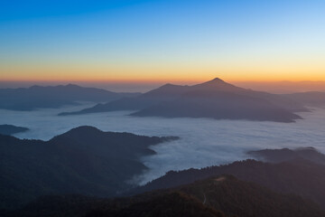 Fototapeta premium Soft sunrise light over misty mountains and layered horizon.