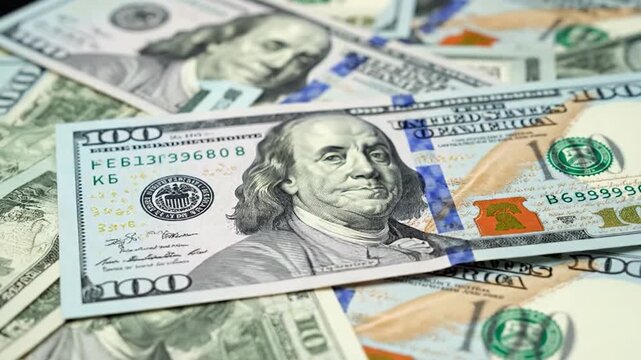 Close-up of American hundred dollar bills, focus on a single note featuring a historical figure