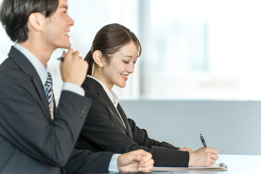 Businessmen and businesswomen in suits standing at a desk (interviewer, company information session)
