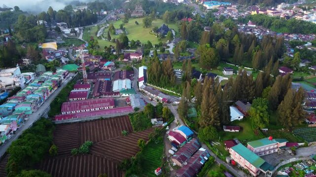 Aerial view of Berastagi town shrouded in thick morning mist and fog with mountain landscape, North Sumatra, Indonesia