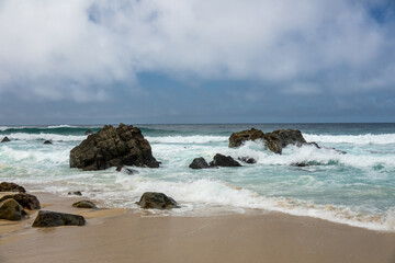 Boulders In The Surf Break Up Waves On A Stormy Day