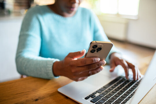Person using smartphone and laptop at home desk