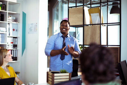 Smiling team leader speaking to colleagues in modern office