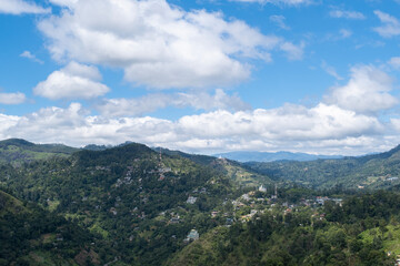 Fototapeta premium Scenic landscape view from the summit of Little Adam’s Peak in Sri Lanka on a sunny day. Lush green hills, dramatic clouds, blue sky and tropical nature create a peaceful and inspiring atmosphere. 