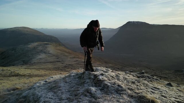 Glen Coe, Scottish Highlands - aerial over the mountains in winter with hill walker hiking forwards