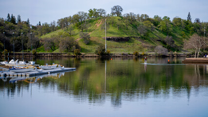 Obraz premium Peaceful Lakeside Recreation with Paddle Boats and Green Hills