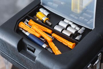 Toolbox organizer with plastic wall plugs socket bits and screwdriver attachments for construction.