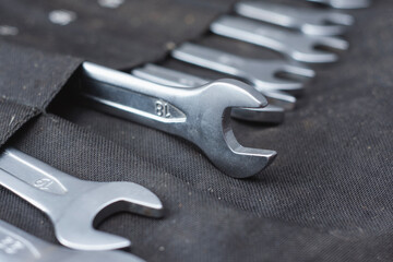 Set of chrome vanadium open end wrenches in a black textile tool roll pouch.