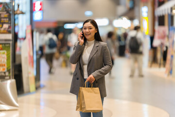woman talking on mobile phone while shopping in shopping mall