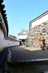 家紋入りの瓦と白壁が続く櫓門への登城路