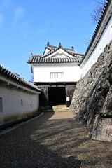 青空に映える日本の城郭：白い漆喰壁と重厚な櫓門への道