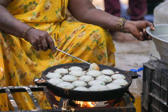 A woman is making kuzhi paniyaram on a pan 