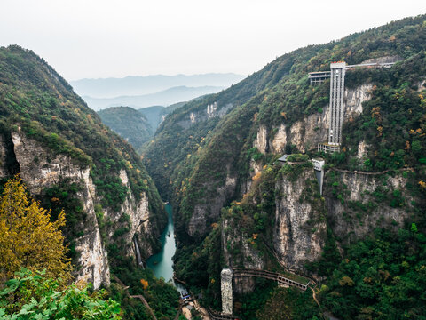 Panoramic view of Bailong Elevator on a cliff above Baofeng Lake in Zhangjiajie, China. World's tallest outdoor lift surrounded by dramatic canyon and lush green mountains.