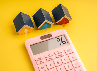 Mini house models with arrows and calculator showing percentage sign, representing mortgage...