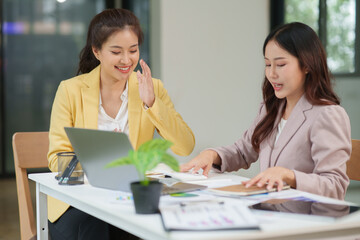 Obraz premium Two Asian businesswomen working with documents in an office.