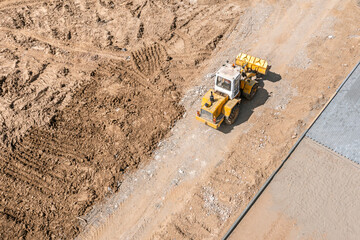 yellow wheel loader on building site. heavy construction machine. aerial view from flying drone.