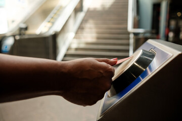 Woman validating train ticket at subway station entrance