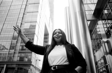 Businesswoman hailing taxi in front of modern office buildings