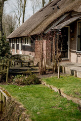 Giethoorn, Netherlands, April 08 2018: Quaint thatched-roof house surrounded by lush greenery and a tranquil canal