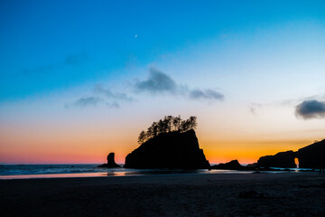 Scenic view of Second Beach at sunset in Olympic National Park, Washington State. Dramatic sea stacks, golden sky, and peaceful waves along the rugged Pacific Northwest coast.