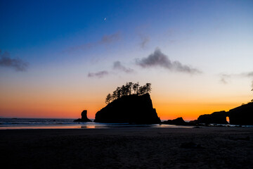 Scenic view of Second Beach at sunset in Olympic National Park, Washington State. Dramatic sea stacks, golden sky, and peaceful waves along the rugged Pacific Northwest coast.