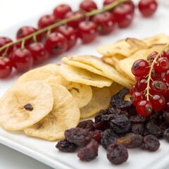 Fresh red currants and dried fruits with crispy banana chips on white plate white background