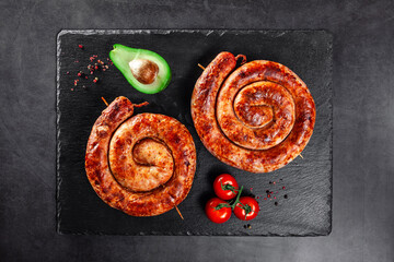 Grilled spiral sausages on black slate