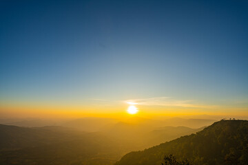 A breathtaking sunset over layered mountain ranges, with warm golden light fading into a deep blue sky, creating a serene and expansive natural landscape ideal for travel and nature themes. © Narong Niemhom