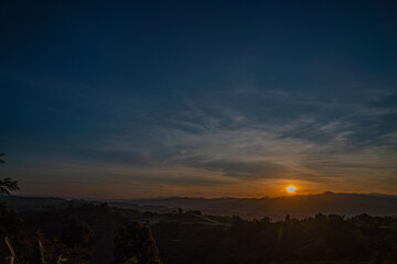 A breathtaking sunset over layered mountain ranges, with warm golden light fading into a deep blue sky, creating a serene and expansive natural landscape ideal for travel and nature themes. © Narong Niemhom