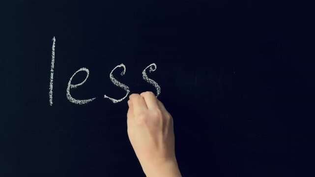 Female hand writing the words "Lesson 2" in chalk on black slate board. Continuing education, second step in learning series.