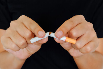 Close-up of a woman hands breaking a cigarette in half, quit smoking and tobacco free concept for healthy lifestyle and healthcare campaign