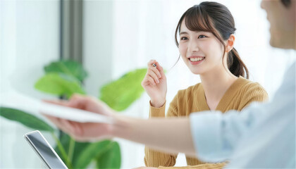 対面の相手から書類を受け取り笑顔を見せる女性社員